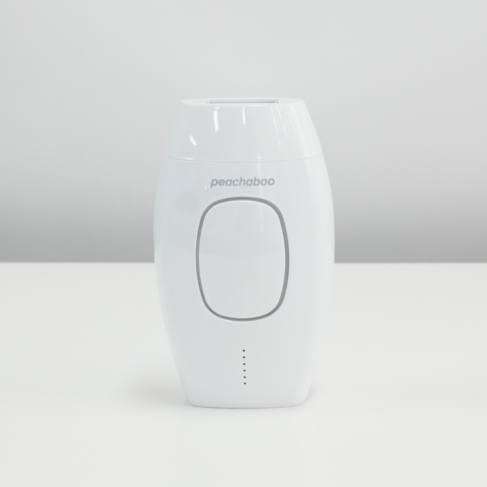 A white Peachaboo Laser IPL hair remover device placed on a table, ready for use in hair removal treatments.