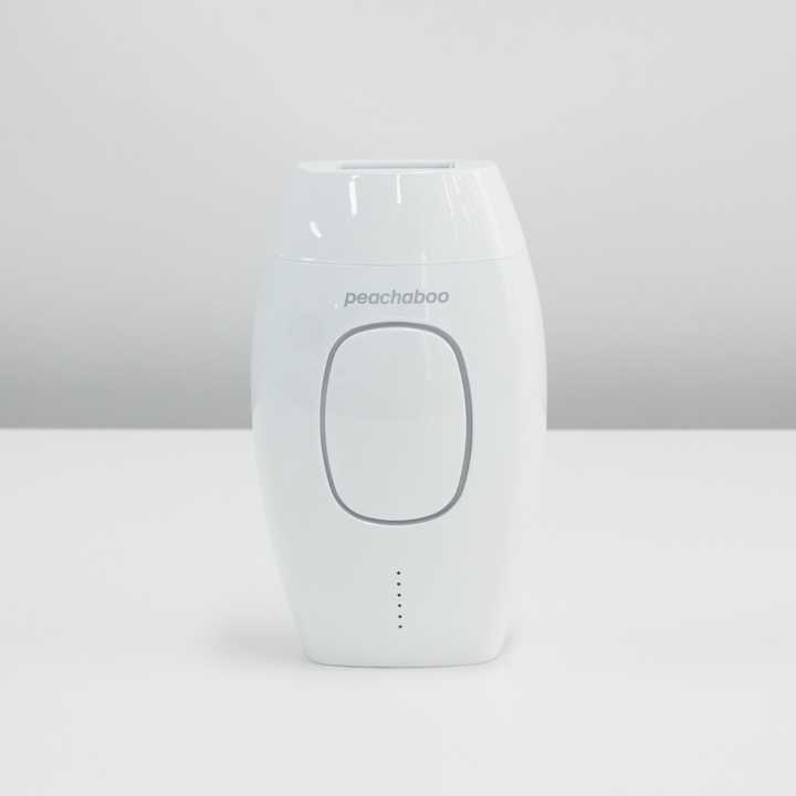 A white Peachaboo Laser IPL hair remover device placed on a table, ready for use in hair removal treatments.