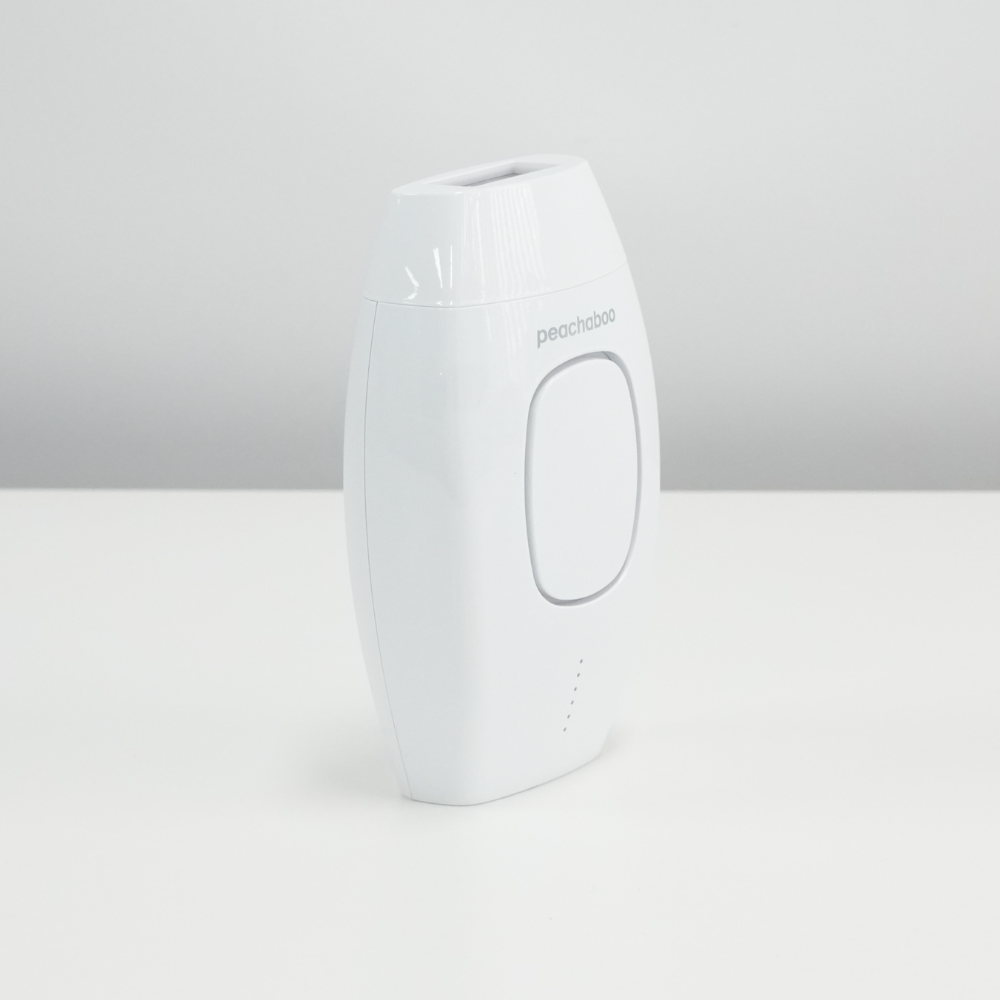 The Peachaboo Laser IPL, a white hair removal device, sits on a table, showcasing its modern design and functionality.