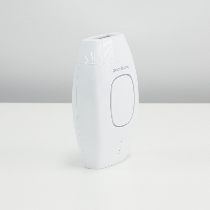 The Peachaboo Laser IPL, a white hair removal device, sits on a table, showcasing its modern design and functionality.